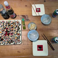 Table filled with a vegan sushi plate, some plates, drinks and a baby monitor
