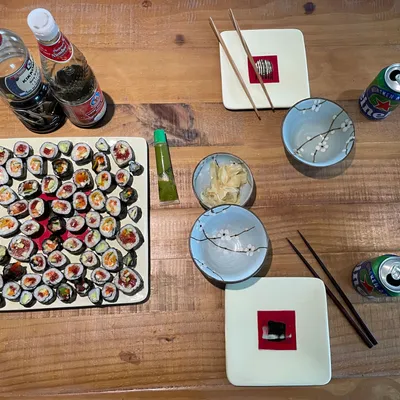 Table filled with a vegan sushi plate, some plates, drinks and a baby monitor
